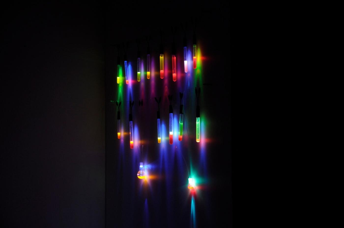 Des ampoules et des éprouvettes renferment, pour des tests de durée, divers liquides fluorescents éclairés par des LED de différentes couleurs.